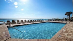 A rectangular swimming pool with clear blue water, surrounded by a tiled deck. - Large Luxury 2 Bedroom, 2 Bath Direct Ocean Front (Daytona Beach)