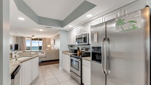 A modern kitchen with white cabinets, stainless steel appliances, and a large refrigerator. - Large Luxury 2 Bedroom, 2 Bath Direct Ocean Front (Daytona Beach)