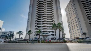A high-rise building with multiple floors, a central entrance, and palm trees in front. - Large Luxury 2 Bedroom, 2 Bath Direct Ocean Front (Daytona Beach)