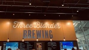Interno di un ristorante con un grande cartello che recita 'Three Blondes BREWING'.