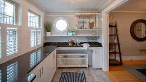 Une cuisine avec une fenêtre, un évier, un plan de travail et un radiateur blanc.