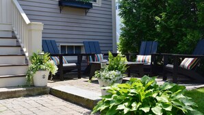 Une terrasse avec des sièges extérieurs, des plantes en pot et un escalier menant à un bâtiment.