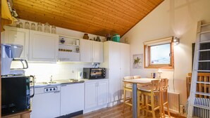 A compact kitchen with white cabinets, a built-in oven, and a dining area with wooden chairs and a table. - 1 bedroom nice home in Bohus-Malmön (Bohus-Malmön)