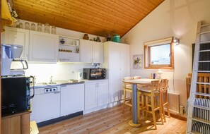 Enjoy meals in a warm kitchen with microwave and stove, complemented by a dining area with a round table and chairs.