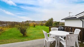 A deck with a table and chairs overlooking a grassy area with trees and a distant view of a hilly landscape. - 1 bedroom nice home in Bohus-Malmön (Bohus-Malmön)
