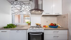 Une cuisine moderne avec des meubles blancs, une cuisinière à gaz, un four et une fenêtre ornée d’un motif décoratif.