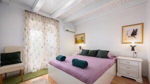 Une chambre à coucher avec un lit, une chaise, une table de chevet et un tableau au mur.