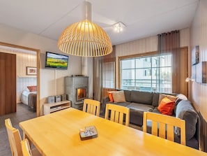 A cozy living room with a wooden dining table, a sofa, and a fireplace. - Rukatonttu d 14 by Interhome (Kuusamo)