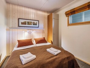 A bedroom with a bed, pillows, a framed picture, and a window with blinds. - Rukatonttu d 14 by Interhome (Kuusamo)
