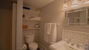 Ein Badezimmer mit Toilette, Waschbecken mit Spiegel und Ablageflächen über der Toilette.