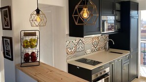 A modern kitchen with dark cabinets, a patterned backsplash, and a wooden countertop. - Cozy apartment in Santa Pola with WiFi (Santa Pola)
