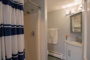 Une salle de bain avec une douche, un lavabo avec un miroir et un porte-serviettes.