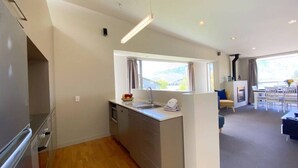 A modern kitchen with a built-in island, a dining area with a table and chairs, and a view of the outdoors.