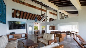 A spacious living area with a high ceiling, wooden furniture, a flat-screen TV, and a foosball table.