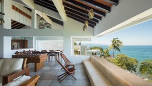 A spacious living area with a foosball table, wooden furniture, and a view of the ocean.