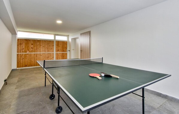 A ping pong table in a room with a wooden door and a window.