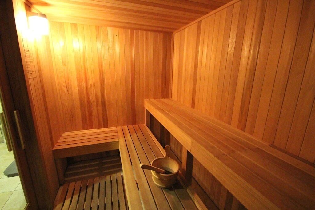 Eine Holzsauna mit Bänken und einem Eimer.