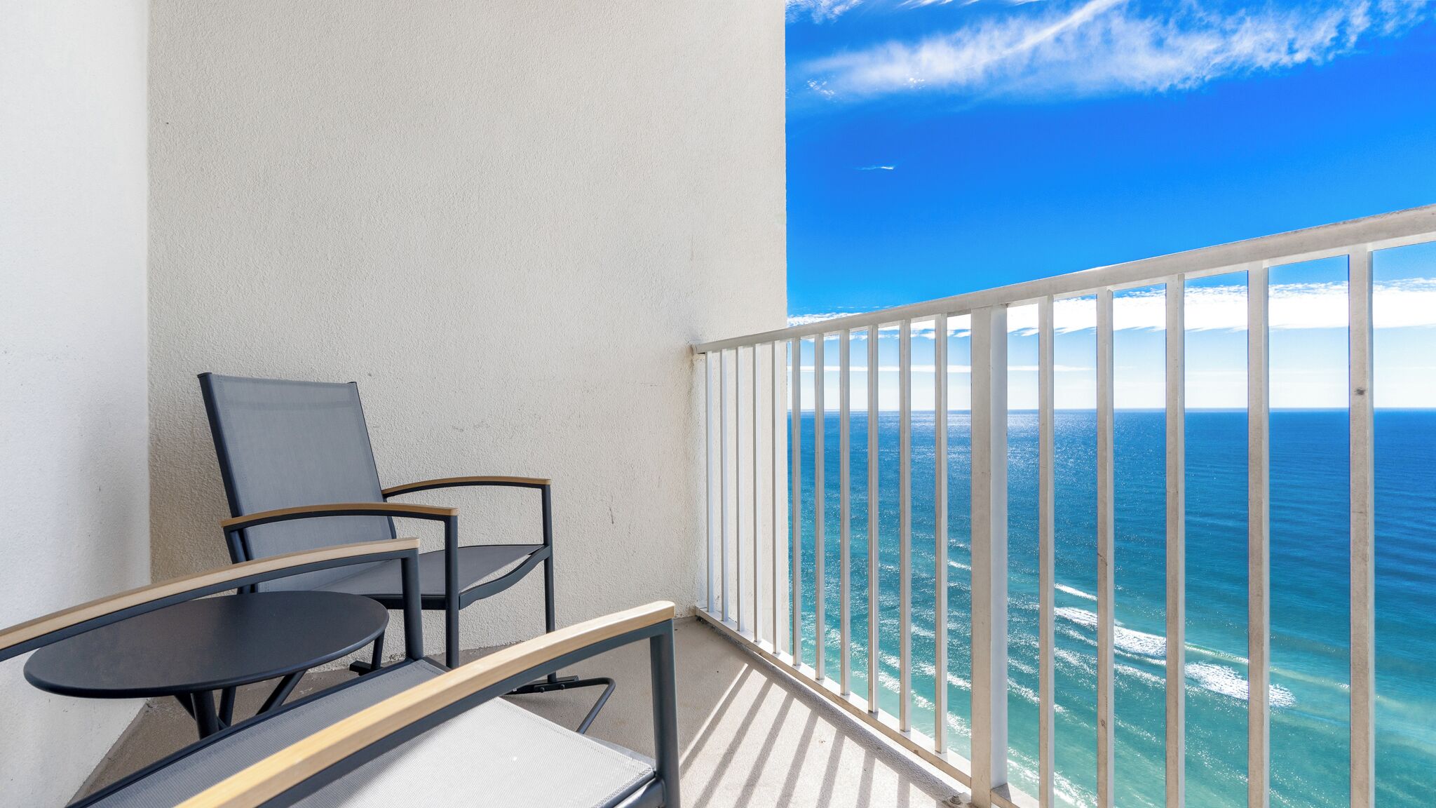 Un balcon avec vue sur l’océan, une chaise et une petite table.