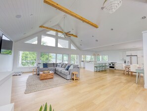 Ein geräumiger Wohnbereich mit einer großen Couch, einem Couchtisch und Blick ins Freie durch große Fenster.
