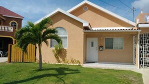 Une maison de plain-pied à l’extérieur beige, avec une porte blanche et un petit porche.