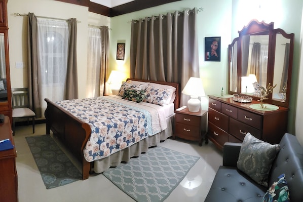 Une chambre à coucher avec un lit, une commode, une chaise et un canapé.