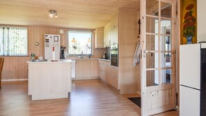 Eine moderne Küche mit Holzausstattung, einer zentralen Kochinsel und einem großen Fenster.