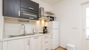 A compact kitchen with a sink, stove, and a small trash bin. - 1 bedroom lovely apartment in Barbat na Rabu (Barbat na Rabu)