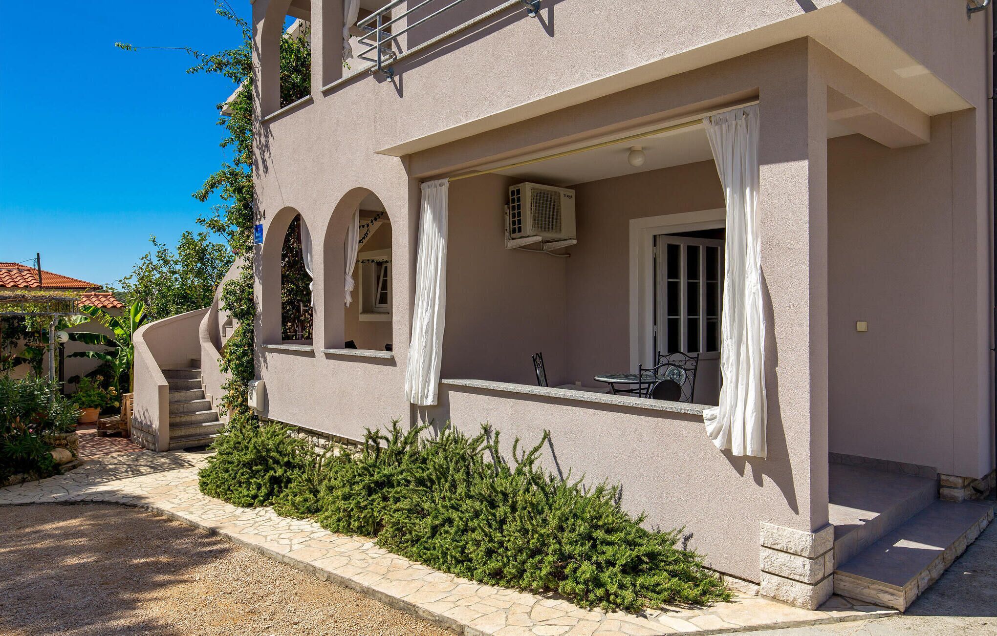 A two-story building with a balcony, a staircase, and a small outdoor seating area.