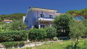A two-story building with a balcony, surrounded by greenery and a clear sky. - 1 bedroom lovely apartment in Barbat na Rabu (Barbat na Rabu)