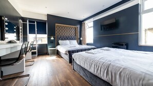 A modern hotel room with two beds, a vanity with mirrors, a desk, and a large window. - Hollywood Suite Sasco Apartments (Blackpool)
