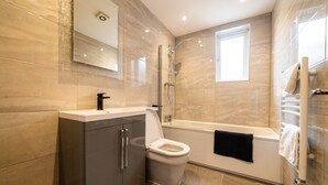 A modern bathroom with a toilet, sink, and bathtub. - Hollywood Suite Sasco Apartments (Blackpool)