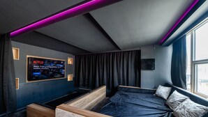 A modern bedroom with a bed, a TV mounted on the wall, and a window. - Hollywood Suite Sasco Apartments (Blackpool)