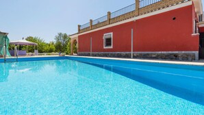 A clear blue swimming pool with a red building in the background. - Beautiful home in Olivares (Olivares)