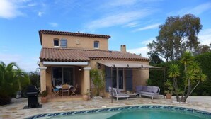Ein Haus mit Swimmingpool, Terrassenmöbeln und einer überdachten Sitzgelegenheit im Freien.