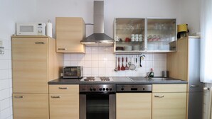Cocina compacta con armarios de madera, microondas, tostadora, estufa y lavavajillas.