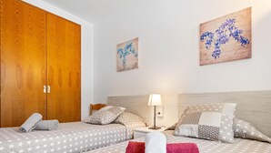 Ein Hotelzimmer mit zwei Betten, Bettwäsche mit Sternenmuster, einem Holzschrank und Wandbildern.