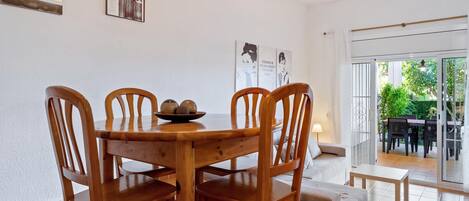 Un comedor con una mesa y sillas de madera, un ventilador de techo y vistas al exterior a través de un ventanal.