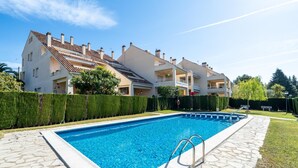 Ein Swimmingpool mit einer Steindeck, umgeben von einer Hecke und einer Reihe von Wohngebäuden.