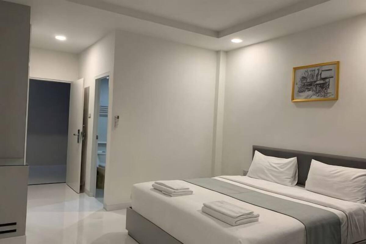 Un dormitorio moderno con cama, una puerta y un cuadro en la pared.