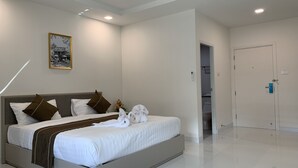 Habitación de hotel moderna con una cama grande, una mesita de noche, un cuadro enmarcado en la pared y una puerta que da a un baño.