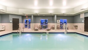 Una piscina con sillas y un puesto de salvavidas, una puerta y una ventana con vistas al exterior.