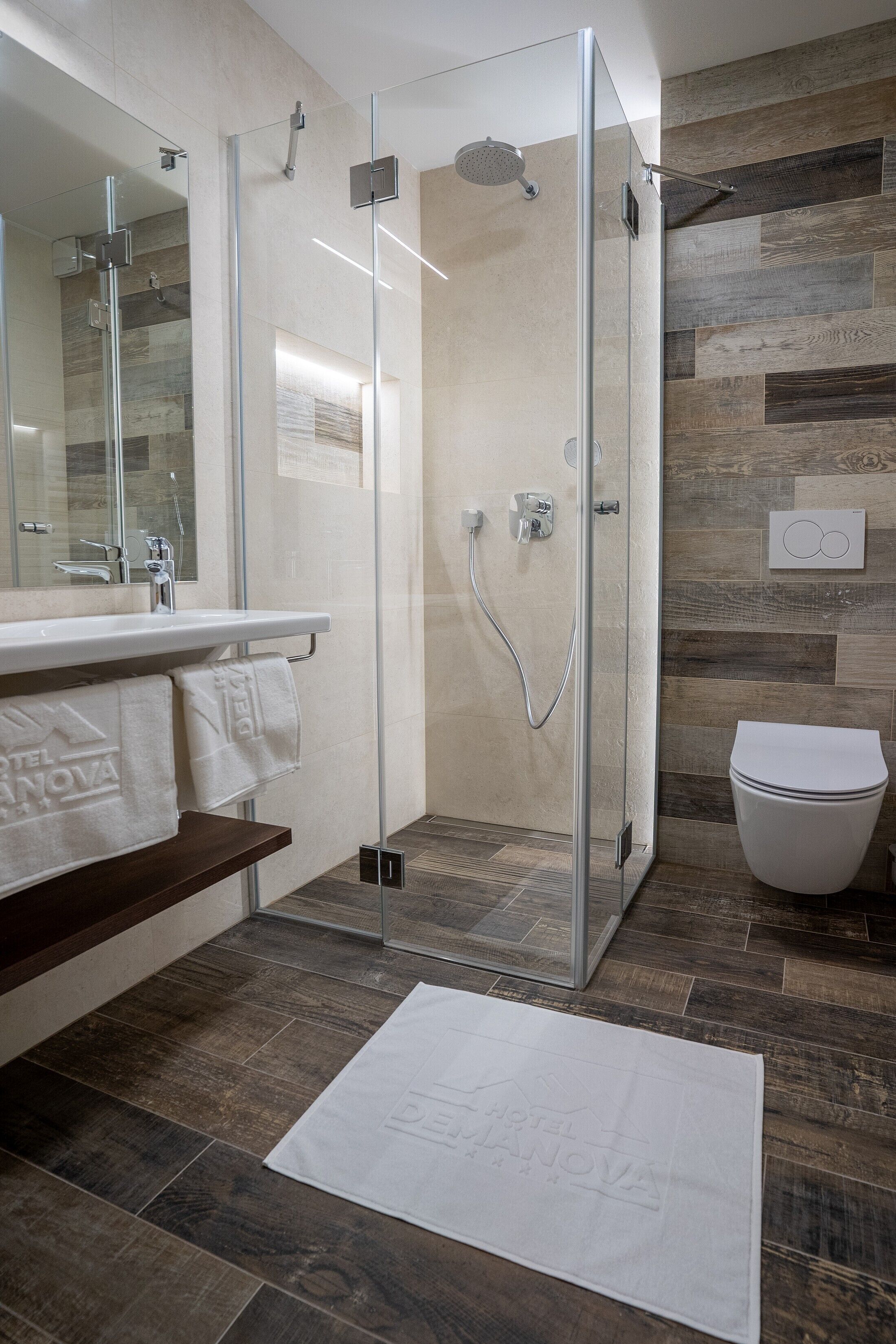 A modern bathroom with a glass-enclosed shower, a white sink, and a toilet.