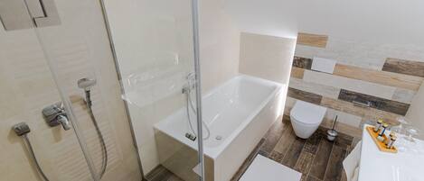 A modern bathroom with a glass-enclosed shower, a standalone bathtub, and a toilet.