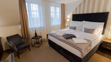 Une chambre d’hôtel avec un grand lit, une chaise, une table de chevet et une fenêtre avec des rideaux.