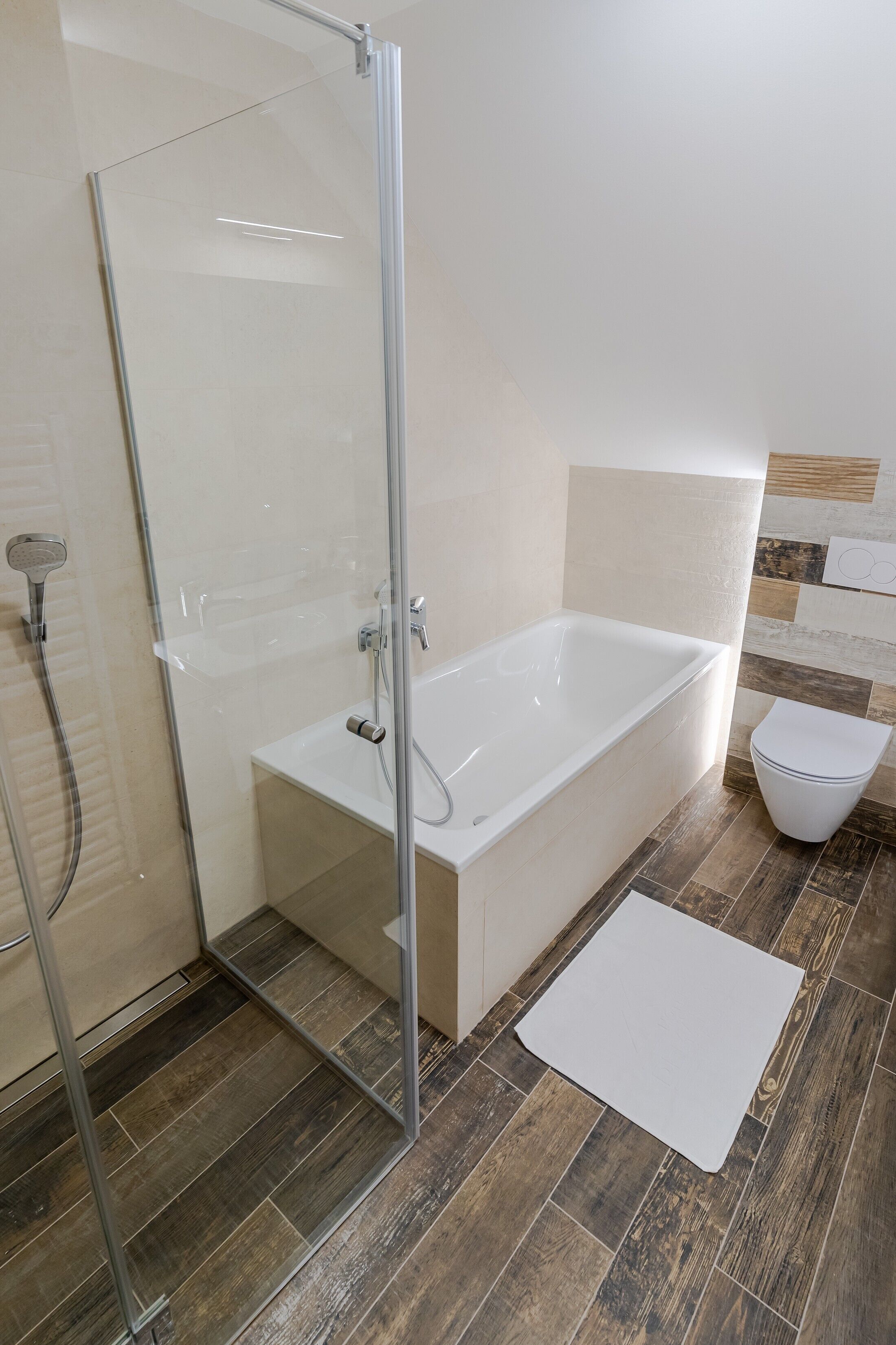 Ein Badezimmer mit Duschkabine aus Glas, einer weißen Badewanne und einem WC.