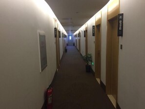 A hotel hallway with doors on both sides, a fire extinguisher, and a potted plant. - Greentree Inn Beijing Tongzhou District Yujiawu Techonology Park Express Hotel (Tongzhou)