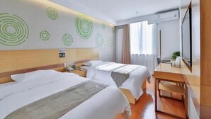 Ein Hotelzimmer mit zwei Betten, einem Holzkopfende, einem Schreibtisch und einem großen Fenster.
