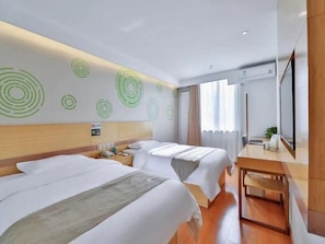 Ein Hotelzimmer mit zwei Betten, einem Holzkopfende, einem Schreibtisch und einem großen Fenster.