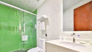 Ein modernes Badezimmer mit Duschkabine aus Glas, einer weißen Toilette und einem Waschtisch mit Spiegel.