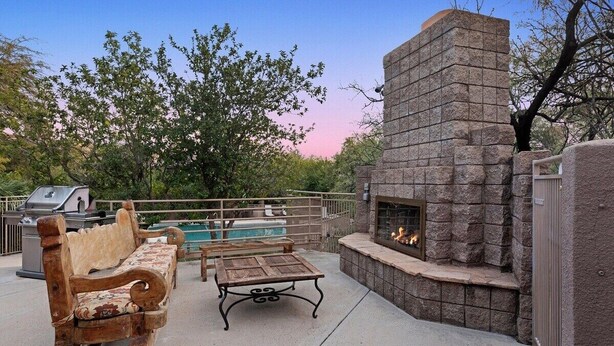 Une terrasse extérieure avec une cheminée en pierre, un banc en bois et un barbecue.